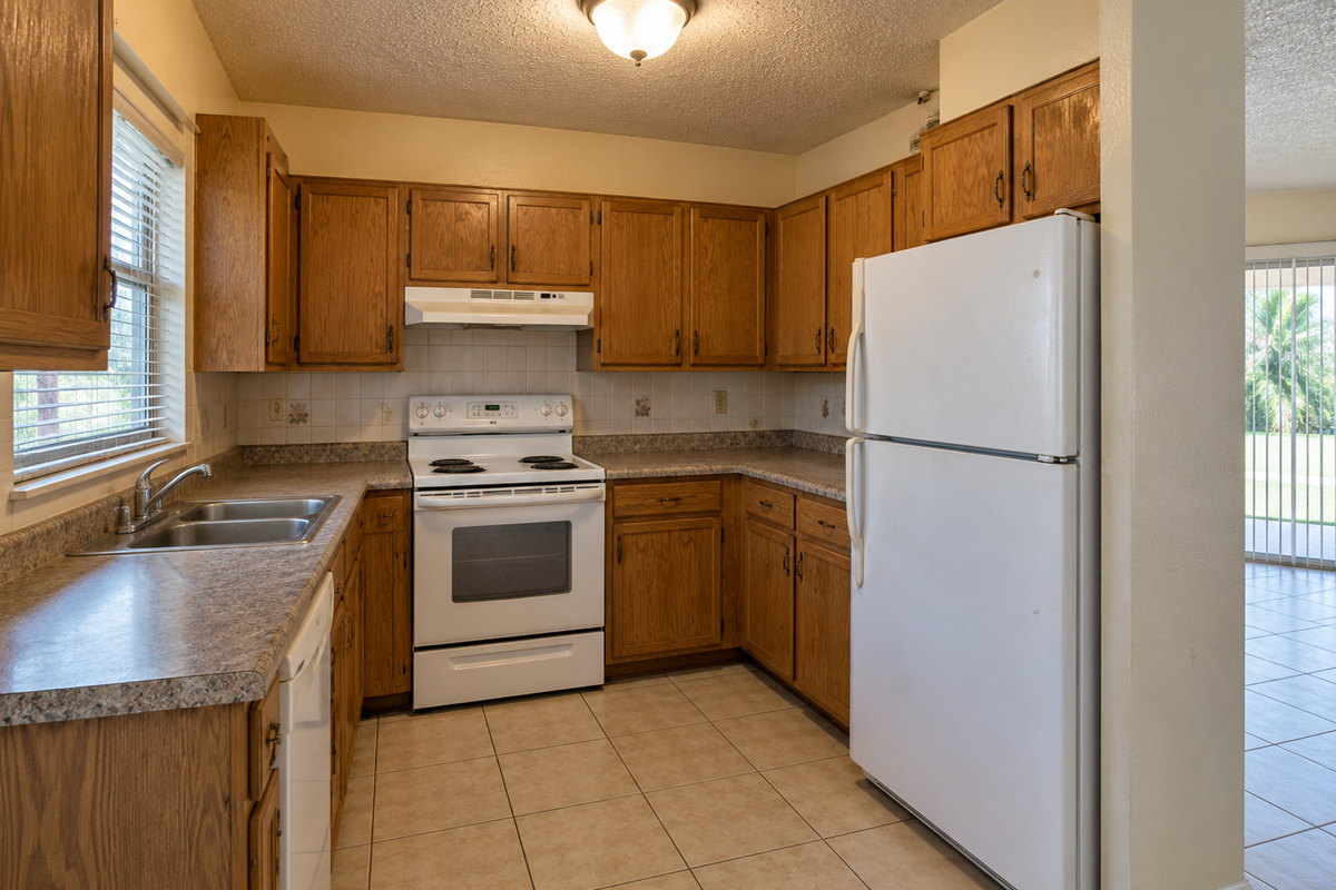The same kitchen before remodeling, with original oak cabinetry, laminate counters and white appliances